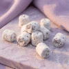parma-lilac-athonite-incense-macro-detail A close up shot of some pieces of Parma Lilac Incense arranged ona marble surface in front of lilac colored drapes.
