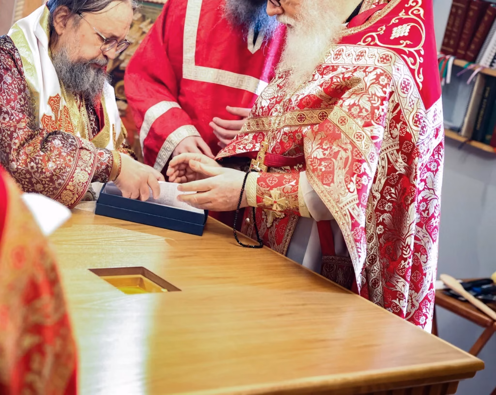 A bishop consecrating a holy table alongside a priest and deacon.